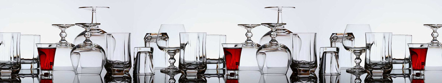 Рюмки, бокалы и стаканы на стеклянном столе